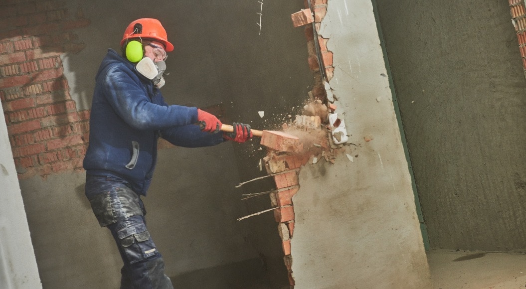 demolition work and rearrangement. worker with sledgehammer destroying wall